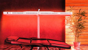 At home setup for Full body red light therapy. Glowing red room with the Beam red light therapy device over a massage table.
