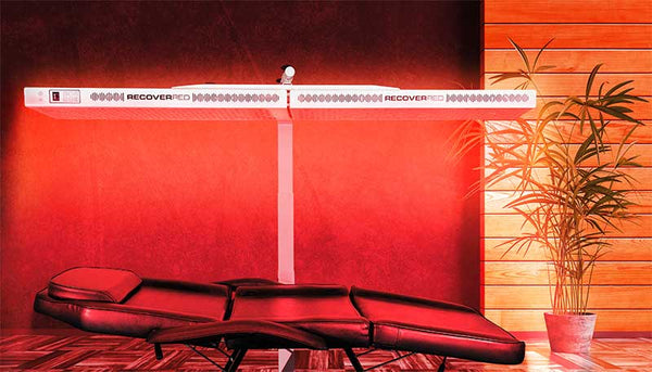 At home setup for Full body red light therapy. Glowing red room with the Beam red light therapy device over a massage table.