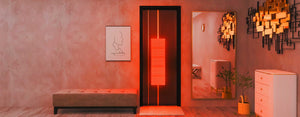 Modern hotel room glowing from a portable red light therapy device that is hanging on the door.