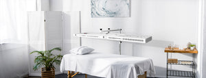 The beam red light therapy device in a clean white room over a massage table.