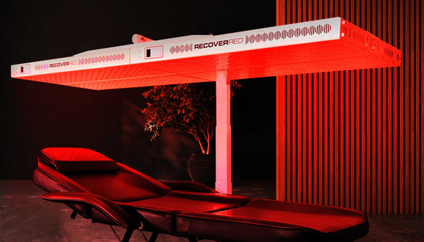 A glowing massage table featuring the Max commercial grade red light therapy device in a modern wellness center.
