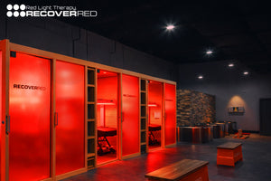 Red glowing privacy rooms behind frosted glass in an athletic recovery center.