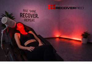 Person receiving targeted red light therapy in a dimly lit room with motivational text on the wall.