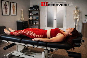 Woman lying on a chiropractic table in a clinic waiting for red light therapy.