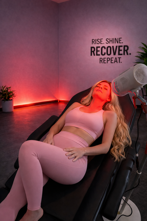 Woman receiving red light therapy in a modern room with motivational wall.text.