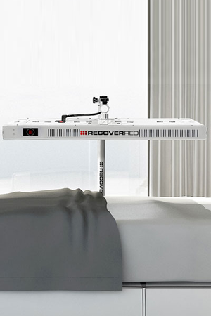 Recover red light therapy device on a white surface with a neutral background over a bed.