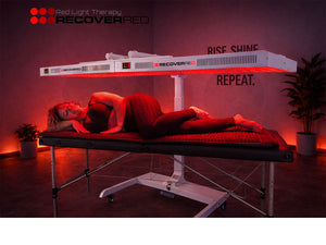 Female receiving whole body red light therapy under a Recover Red device.