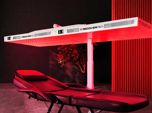 Red light therapy bed with 'Recovered' branding in a dark room.