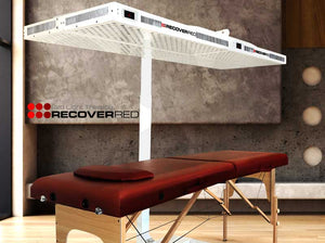 Red light therapy over a wooden massage table against a concrete wall.