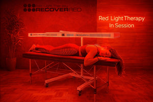 Person receiving full body red light therapy on a massage table.