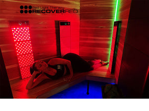 Woman lying inside a red light therapy Infrared sauna with 'RECOVERED' branding.