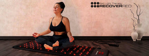 Woman sitting on a red light therapy  plus grounding mat.