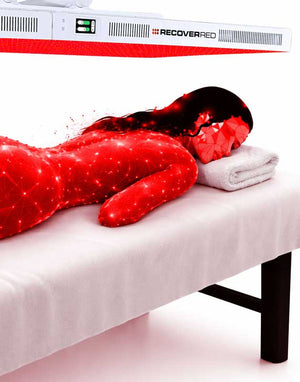 Person lying on a massage table with red light therapy device over the body.