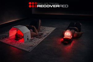 Two people lying on mats with red light therapy devices. 